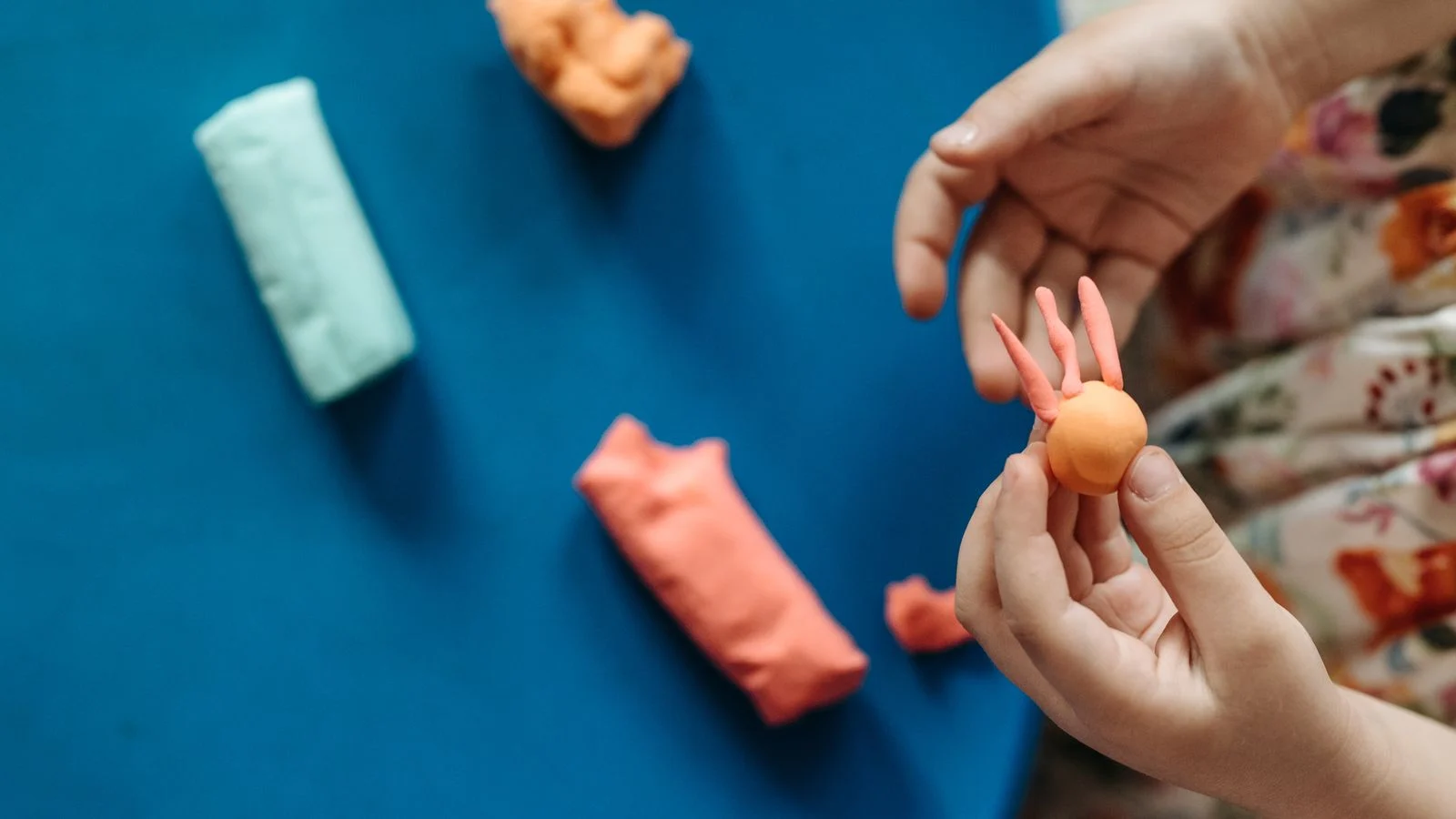Manos de una niña modelando plastilina de colores
