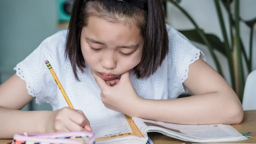 Niña concentrada escribiendo en un cuaderno