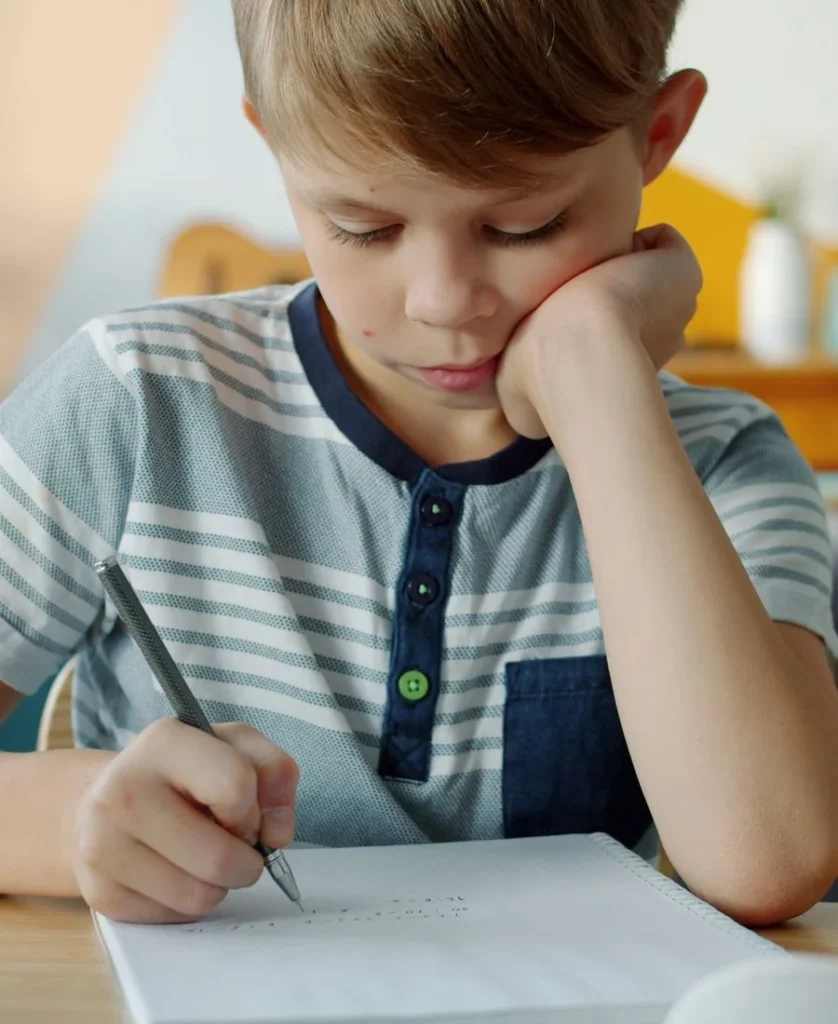 Niño pensando mientras hace la tarea