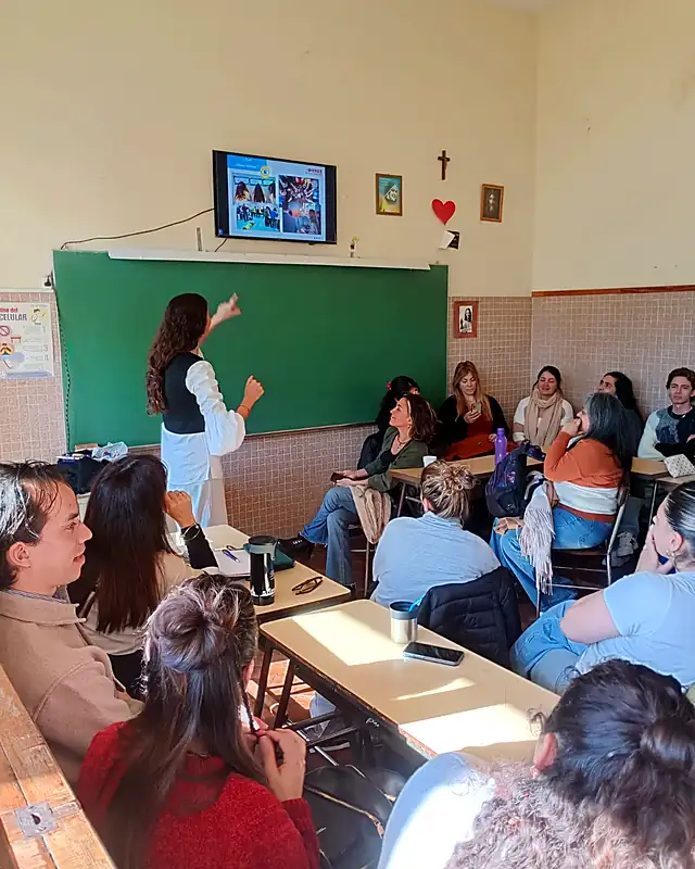 Sophie explica una actividad frente al pizarrón a un grupo de docentes